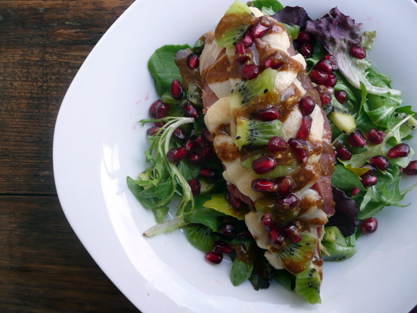 on a bed of greens with Kiwi, Pomegranate, and a Sweet Baslamic Habanero Mustard Drizzle
